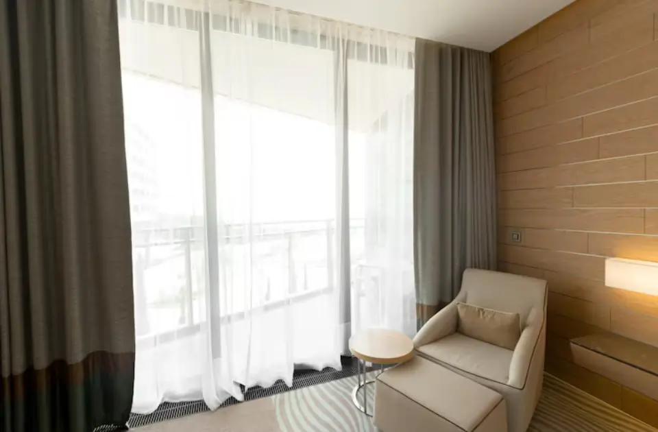 Modern hotel room with elegant curtains and sheer window coverings, providing light control and privacy in a contemporary interior.