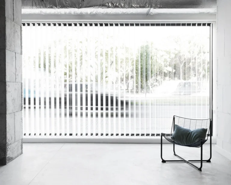 Modern office space with vertical blinds providing light control and privacy, showcasing a minimalist chair in a bright, open environment.